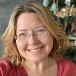 White woman with blonde hair and glasses, smiling