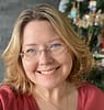 White woman with blonde hair and glasses, smiling