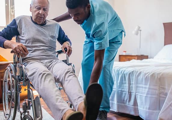 Male, African American nurse assists a patient in a wheelchair